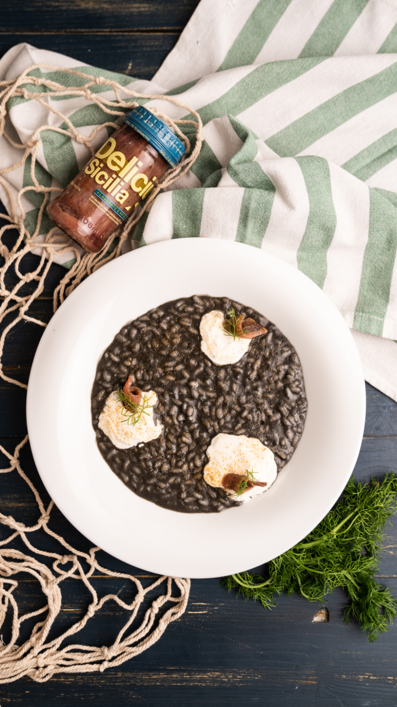 Risotto al nero di seppia con Alici del Canale di Sicilia, stracciatella e polvere di gambero